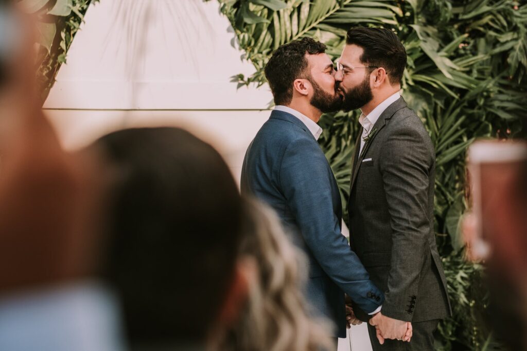 men wearing suit kissing in front of people